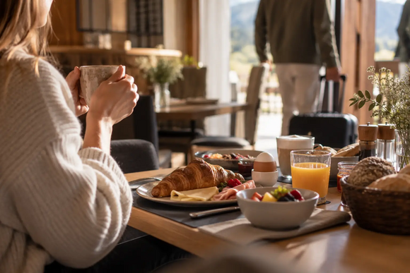 Frau isst Frühstück mit Croissant und Obst in gemütlichem Restaurant